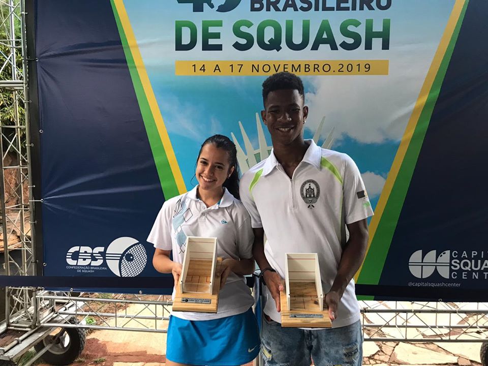 Squashinhos Emanuelle Nunes and João Victor holding their trophies from the Brazilian Squash Championship 