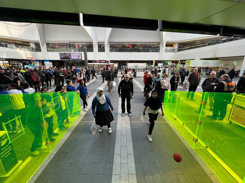 a school plays squash on a mini squash court in new street station